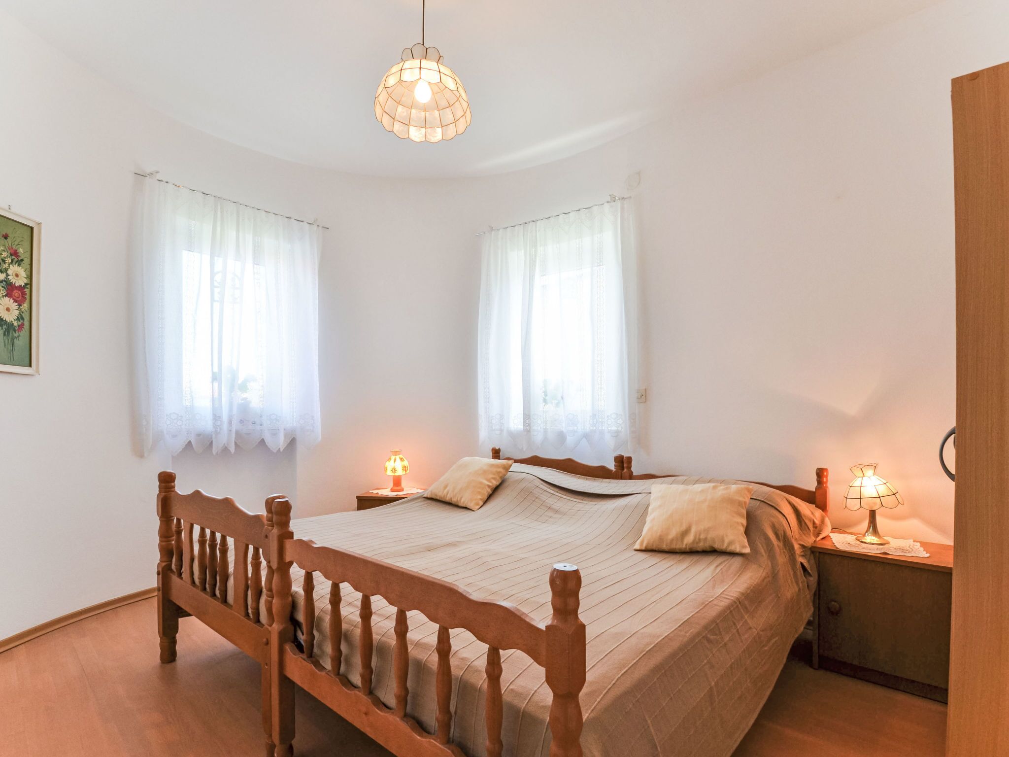 Une chambre à coucher avec un lit en bois, deux tables de chevet avec des lampes et un luminaire suspendu.