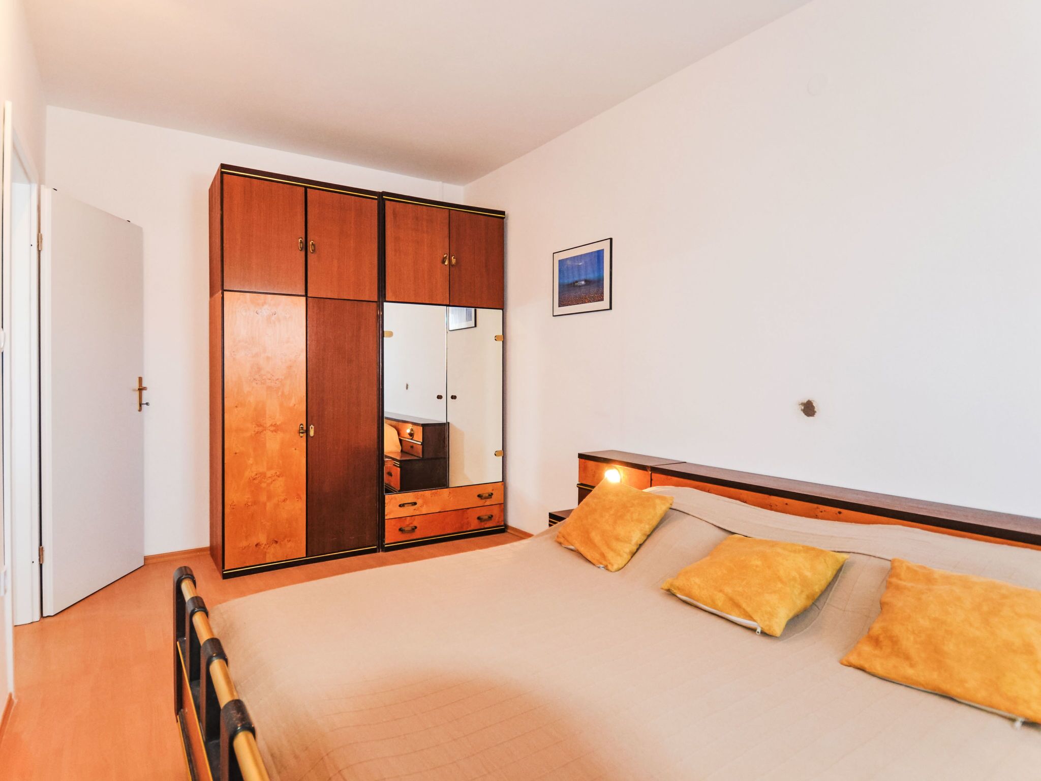 Ein Schlafzimmer mit Bett, Nachttisch, Lampe und Kleiderschrank.