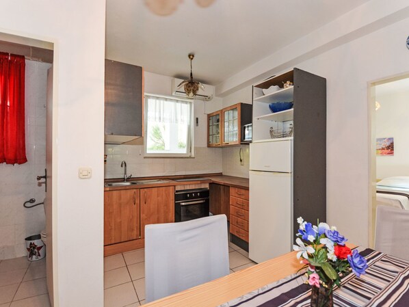 Eine kleine Küche mit Holzausstattung, einem eingebauten Backofen und einem Kühlschrank.