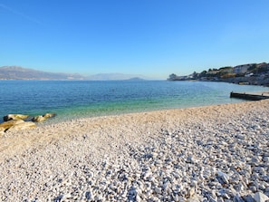 A pebble beach with clear water and distant mountains. - Apartment Jako by Interhome (Trogir/Slatine)