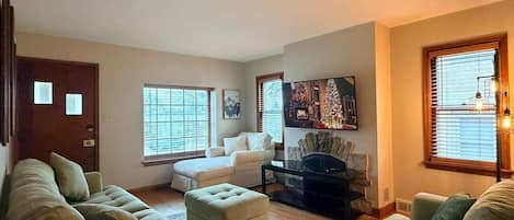A living room with a sofa, ottoman, and a fireplace.
