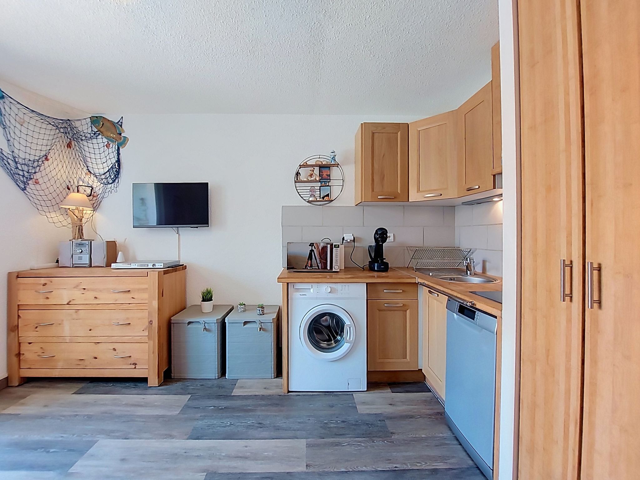 Une cuisine compacte avec des meubles en bois, un lave-linge, un four à micro-ondes et un petit coin repas.