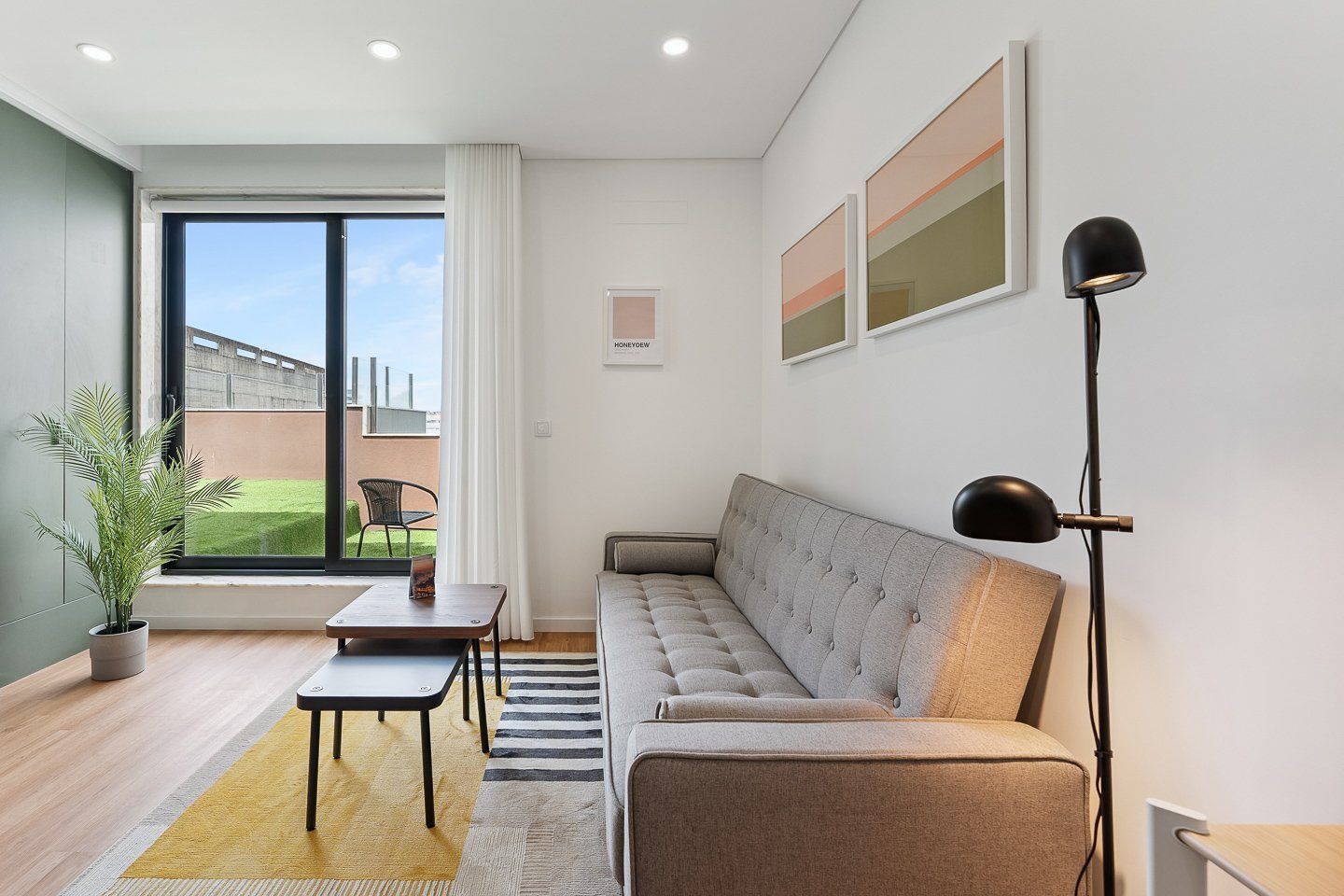 Un salon moderne avec un canapé, une petite table, une lampe sur pied et une plante en pot.