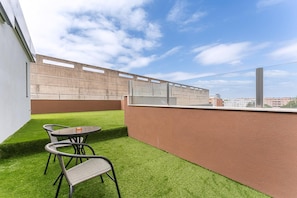 A balcony with artificial grass, a table, and two chairs.