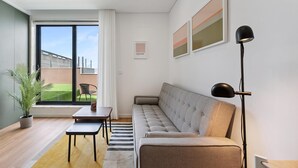 Una sala de estar moderna con un sofá, una mesita, una lámpara de pie y una planta en maceta.