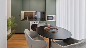 Una cocina moderna con microondas, lavadora y un comedor con mesa redonda y sillas.