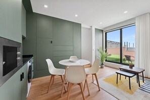 A modern kitchen with a dining area, large windows, and a view of the outdoors. - Guestready - Tutti Frutti Studios (Porto)