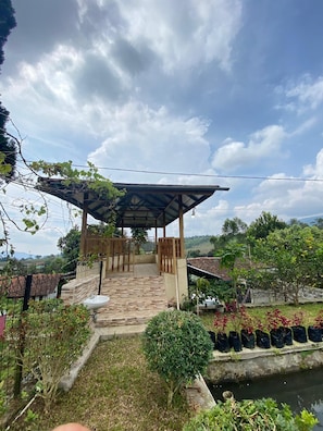 A covered outdoor area with a stone floor, a small sink, and a view of a river. - Cozzy Villa Family Pak Ed Pangalengan (Pangalengan)