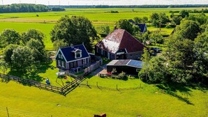 A rural property with a large barn, a house with a sloped roof, and a fenced pasture with horses. - Fantastic family home with large garden (Hippolytushoef)