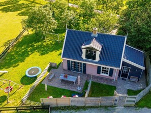 A two-story house with a blue roof, a patio with outdoor furniture, and a fenced backyard. - Fantastic family home with large garden (Hippolytushoef)