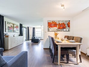 A modern living room with a dining area, featuring a sofa, a dining table with chairs, and artwork on the walls. - Fantastic family home with large garden (Hippolytushoef)