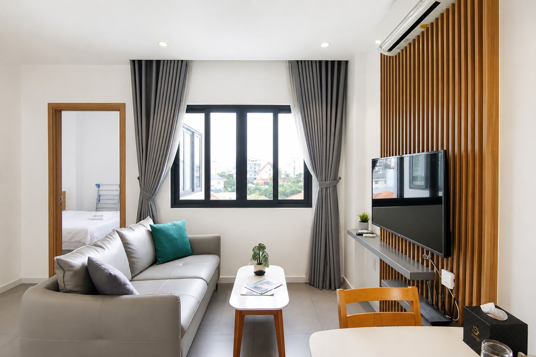 A modern living room with a sofa, a coffee table, a TV, and a view of the outside.