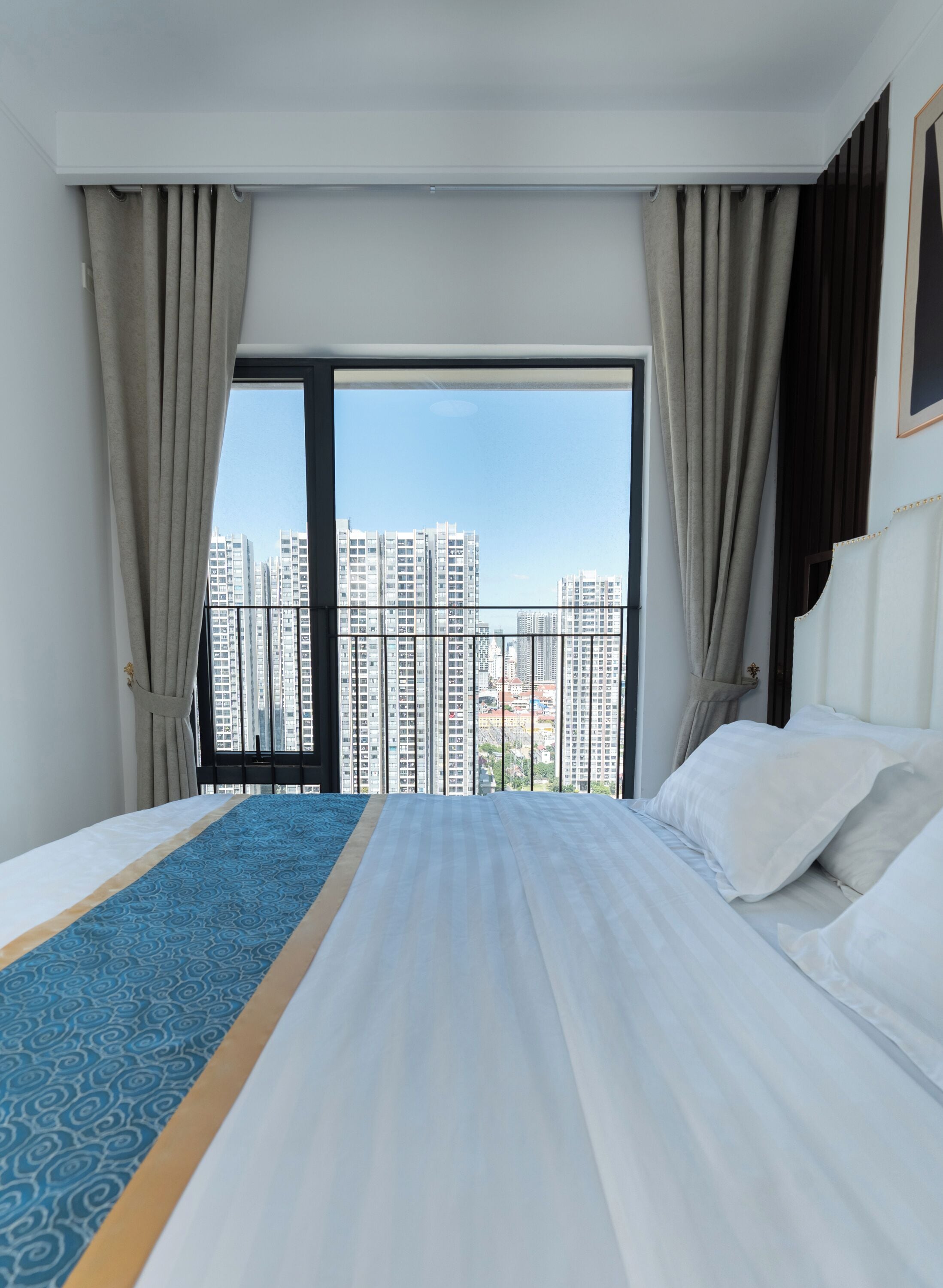 Habitación de hotel con una cama grande, vistas a rascacielos y un balcón.
