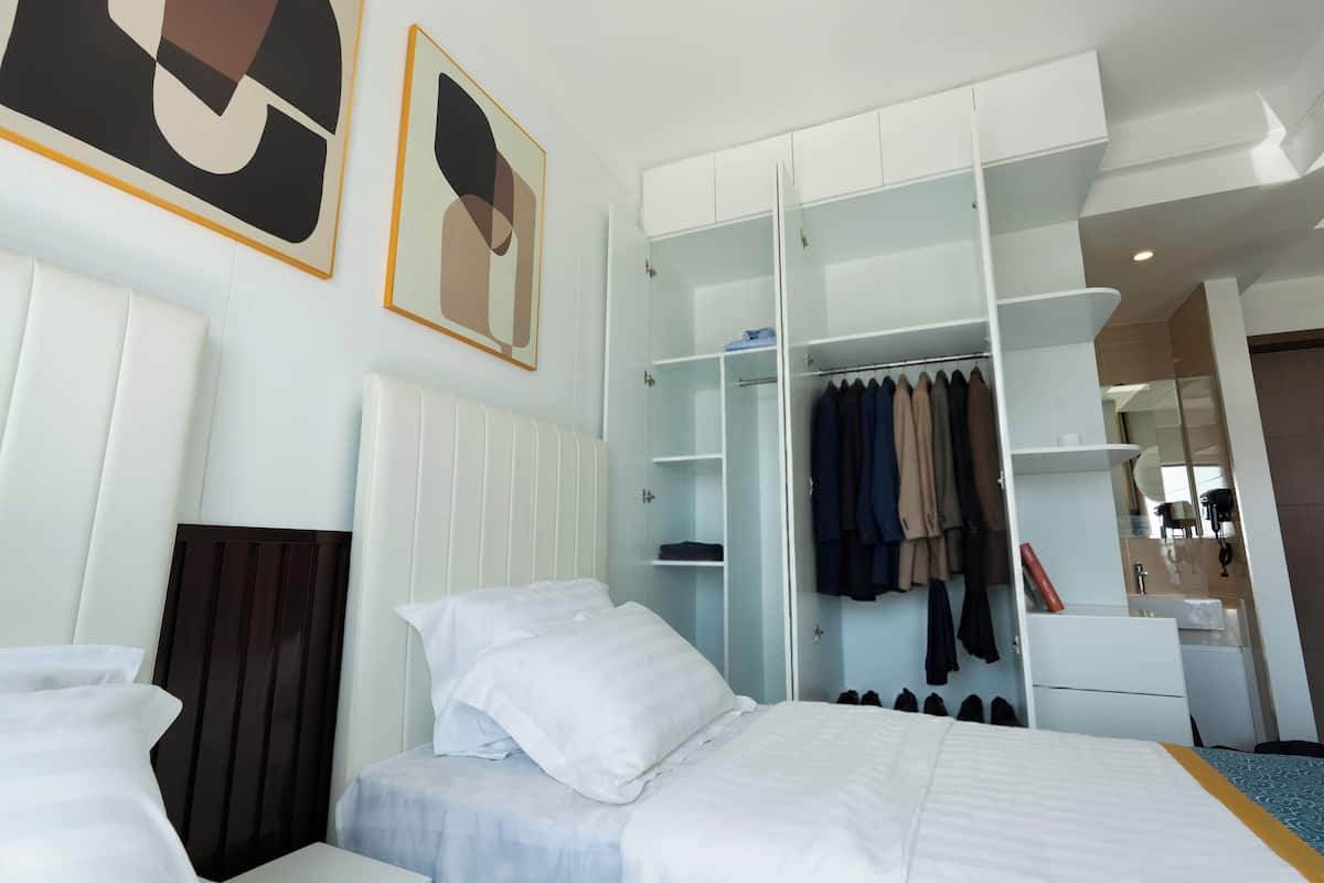 A hotel room with a bed, a wardrobe, and a mirror.