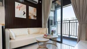 A modern living room with a white sofa, a round wooden table, and artwork on the wall. - MERIDIAN Inn RESIDENCE  (Phnom Penh)