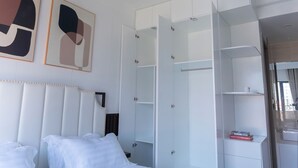 A hotel room with a bed, a ceiling fan, a wardrobe, and abstract art on the wall. - MERIDIAN Inn RESIDENCE  (Phnom Penh)