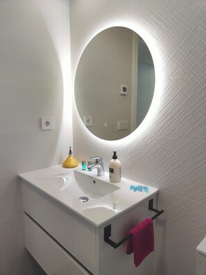 A bathroom with a white sink, a round mirror, and a towel rack. - Casa Seabre (Finestrat)