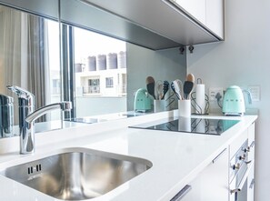 Moderni keittiö, jossa on ruostumattomasta teräksestä valmistetut kodinkoneet, kaksi allasta ja ikkuna, josta on näkymä rakennuksiin.