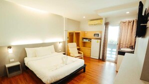 A hotel room with a bed, bedside tables, a desk with a chair, a microwave, and a TV. - Collection O Thaiphiphat House Silom (Bangkok)