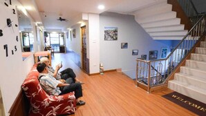 A hotel lobby with a reception desk, a staircase, and a waiting area with a red sofa. - Collection O Thaiphiphat House Silom (Bangkok)