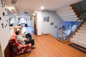 Eine Hotelhalle mit einer Rezeption, einer Treppe und einer Wartebereich mit einem roten Sofa.