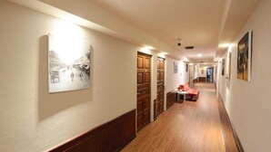 A hallway with wooden flooring, a red sofa, and framed pictures on the walls. - Collection O Thaiphiphat House Silom (Bangkok)