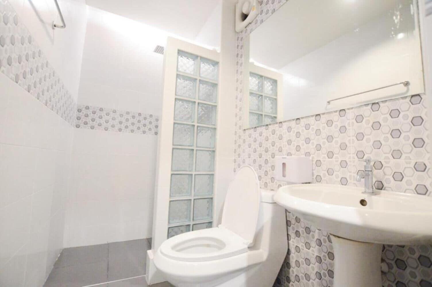 A bathroom with a toilet, a sink, and a shower area.