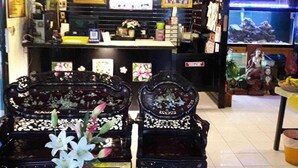 A restaurant interior with a counter, decorative chairs, and a fish tank. - Collection O Thaiphiphat House Silom (Bangkok)
