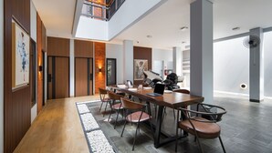 Un espace repas moderne avec une longue table, des chaises et un ordinateur portable. Un escalier mène à un niveau sup érieur.