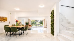 A modern dining area with a marble floor, green chairs, and a table with a vase of flowers. - Elegant 4BR Villa w/ Garden & Terrace (Mödling)