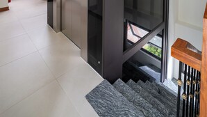 Ein modernes Interieur mit Treppe, Panoramaaufzug und Blick durch ein Fenster.