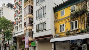 Ein mehrstöckiges Gebäude mit Balkonen, einem sichtbaren Hotelschild und einem Schaufenster mit heruntergelassener Rollgitter.