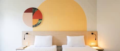 A hotel room with two beds, a wooden headboard, bedside lamps, and a wall art piece.