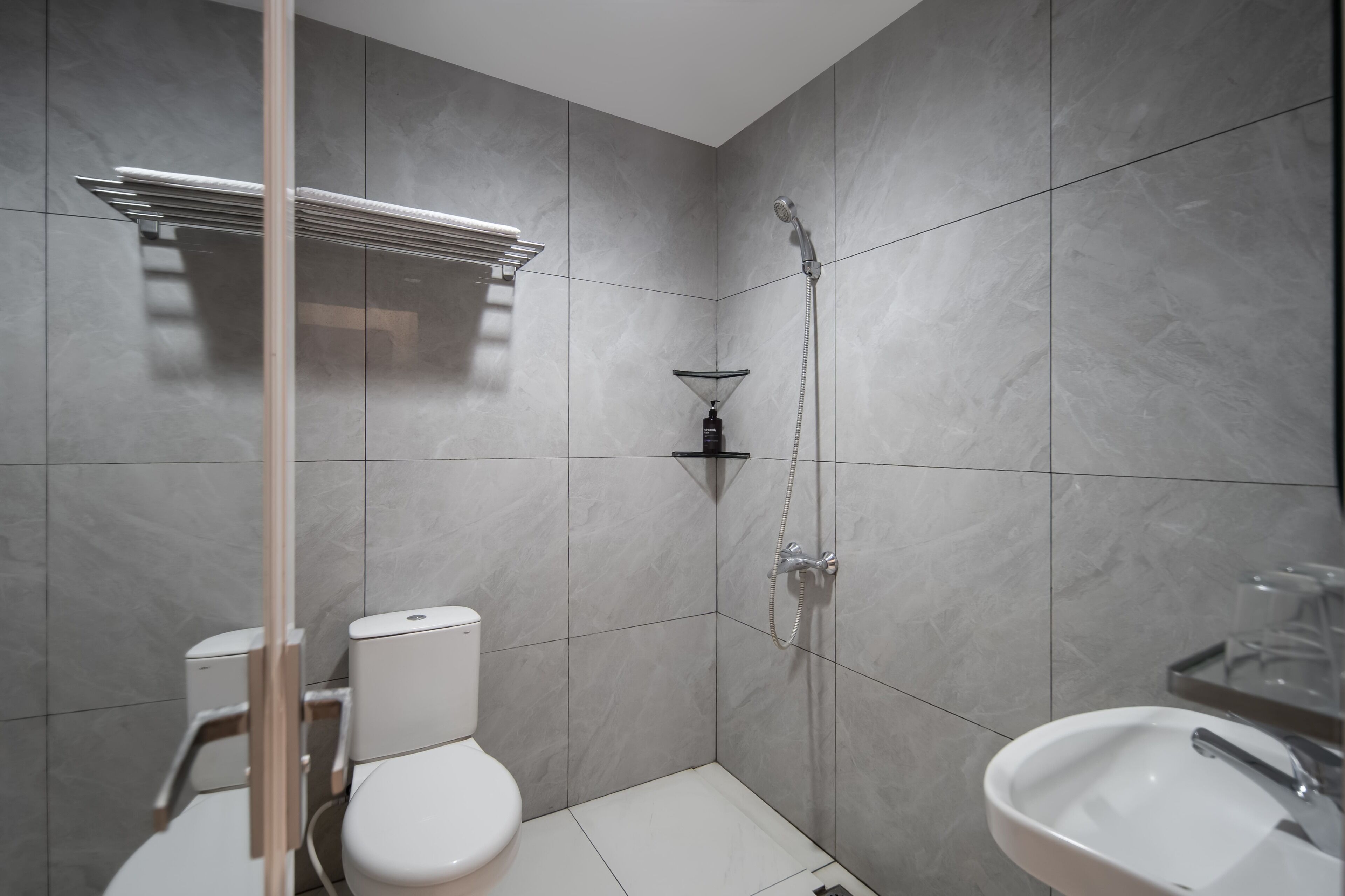 A modern bathroom with a toilet, shower, and sink.