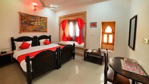 Quarto com cama, escrivaninha, cadeira, janela com cortinas, ventilador de teto e luminária na parede.