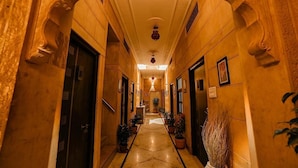 Um corredor com arcos elaborados, piso de mármore e plantas em vasos.