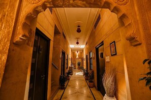 Un pasillo con arcos decorativos, suelo de mármol y plantas en macetas.