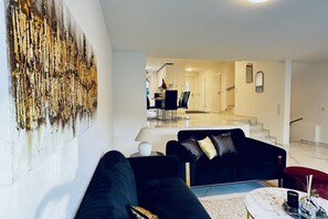 En moderne stue med en sort sofa, et sofabord og et billede på væggen.