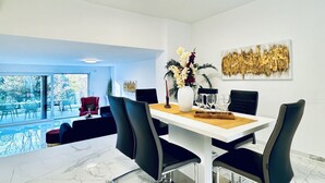 A modern dining area with a white table, black chairs, and a vase of flowers. - Quiet Luxury 5BR & 1LR Villa w/ Garden & Terrace (Mödling)