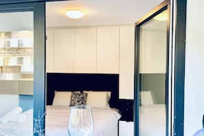 Et hotelværelse med en seng, et glas vand og udsigt ud.