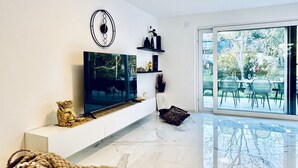 A modern living room with a flat-screen TV, a fireplace, a large window, and a dining area visible through the glass doors. - Quiet Luxury 5BR & 1LR Villa w/ Garden & Terrace (Mödling)