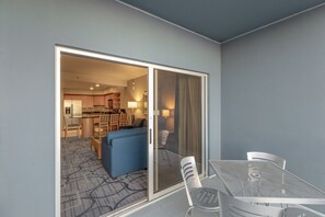 A hotel room with a sliding glass door leading to a kitchenette, a dining area with a table and chairs, and a blue sofa. - Vegas Condo - Pool, Hot Tub & Balcony Views (Las Vegas)