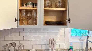 A kitchen with a marble countertop, a cabinet with glassware, and a sink.