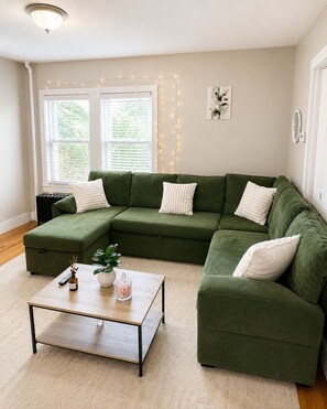 Ein modernes Wohnzimmer mit einem Ecksofa, einem Couchtisch und einer Heizung.
