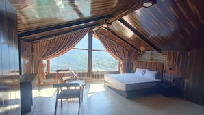 Un dormitorio con un ventanal grande, una cama, una silla y una mesa.