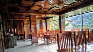 Un espacio interior amplio con muebles de madera, ventanas grandes y vistas al exterior.
