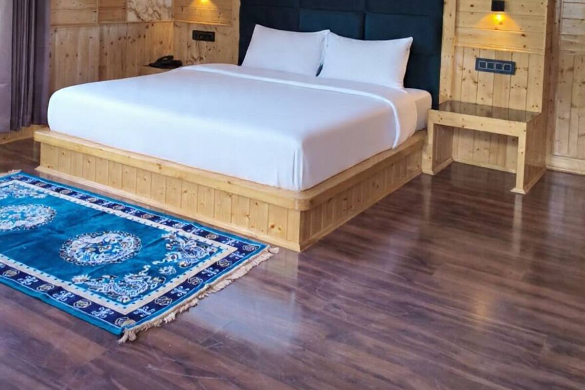 A wooden-paneled room with a bed, nightstands, and a blue patterned rug.