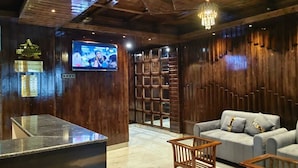 Un vestíbulo con mostrador de recepción, televisión, sofá y estantería de madera.
