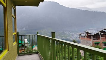 A balcony with a green railing overlooking a mountainous landscape.