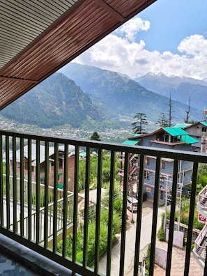 Un balcon offrant une vue sur un paysage montagneux, une ville en contrebas et un bâtiment doté d’un toit végétalisé.